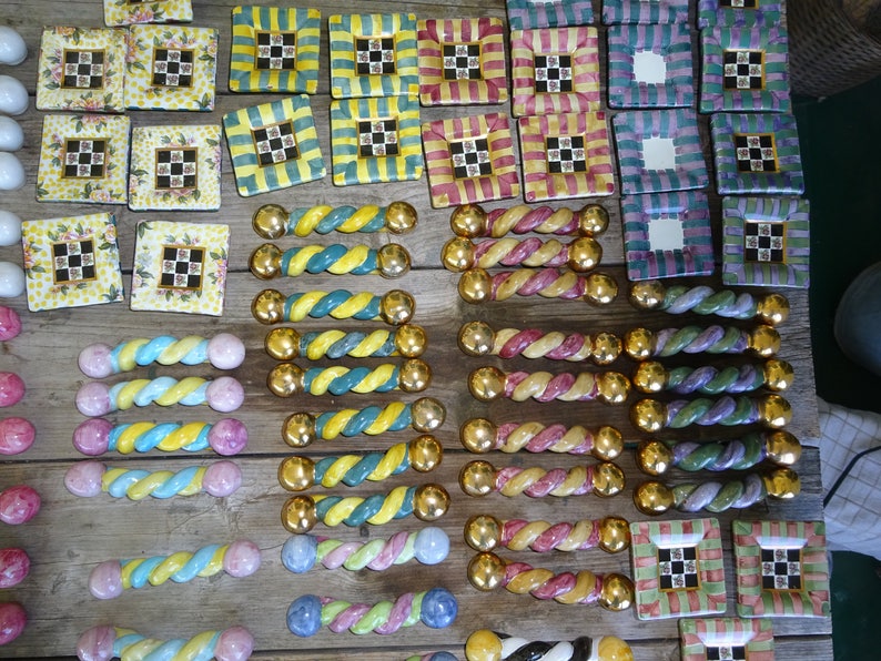 Puede incluir: Una colecci&oacute;n de coloridos pomos de cer&aacute;mica decorativos y baldosas cuadradas con varios dise&ntilde;os. Los pomos tienen un dise&ntilde;o retorcido con extremos dorados. Las baldosas presentan dise&ntilde;os florales, a cuadros y a rayas en tonos amarillos, verdes, rosas y azules.