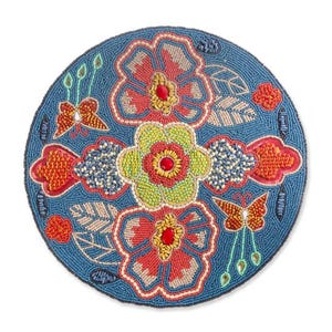 May include: A round, beaded coaster with a blue background. The coaster features a floral design with red, yellow, and green flowers, along with butterflies and leaf accents. The beads are in various colors, creating a detailed pattern.