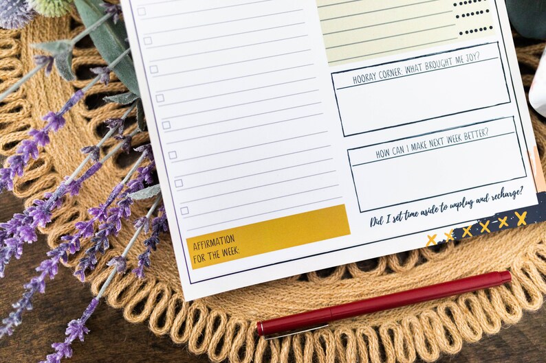 May include: A weekly planner with a checklist, space for affirmations, and prompts for reflection. The planner has a yellow and black design with the text "Hooray Corner What Brought Me Joy?", "How Can I Make Next Week Better?", and "Did I Set Time Aside To Unplug And Recharge?"