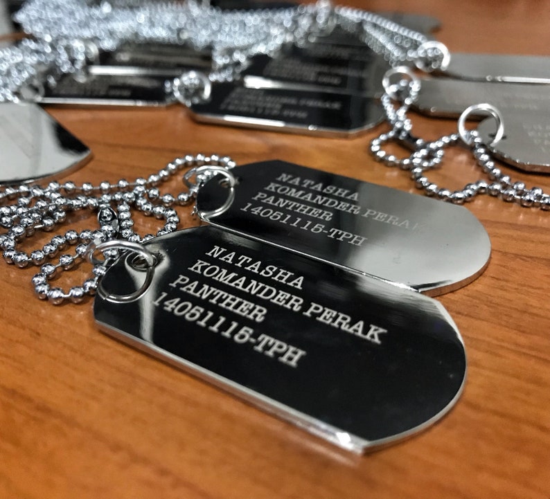May include: Two silver dog tags with a silver chain. The tags are engraved with the text "Natasha Komander Perak Panther 14061116-TPH".