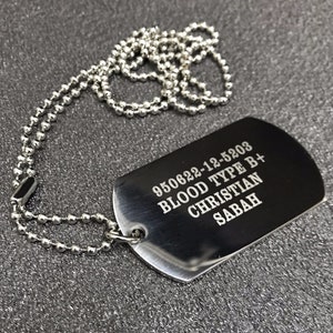 May include: A silver dog tag necklace with a silver chain. The dog tag is engraved with the text "950622-12-5203 BLOOD TYPE B+ CHRISTIAN SABAH".