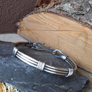 Peut inclure: Un bracelet en argent avec un design de fil torsadé et un fermoir à crochet.