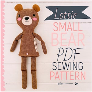 May include: A handmade brown bear doll with a white face, pink cheeks, and small brown ears. The doll is standing on a white wooden surface. Text on the image reads "Lottie Small Bear PDF Sewing Pattern".