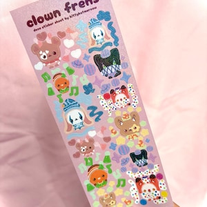 May include: A sheet of decorative stickers with a pink background featuring the text "clown frens". The stickers include various cartoon clown characters, musical notes, hearts, and stars in pastel colours. The stickers are designed by kittykatmersow.
