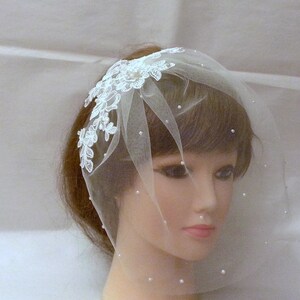 May include: A white bridal veil with a delicate lace design and pearl embellishments. The veil is made of soft tulle and is perfect for a simple and elegant wedding look.
