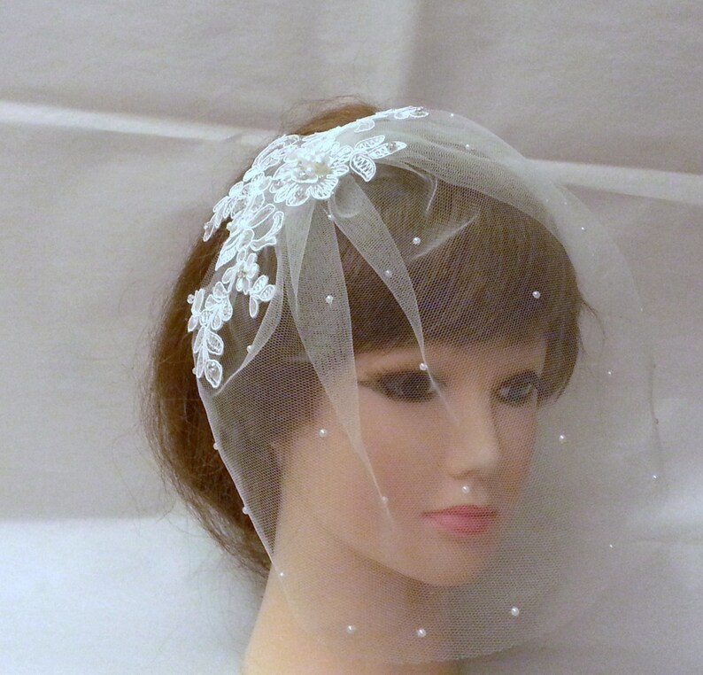 May include: A white bridal veil with a delicate lace design and pearl embellishments. The veil is made of soft tulle and is perfect for a simple and elegant wedding look.