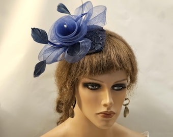 Könnte beinhalten: Ein blauer und schwarzer Fascinator mit Blumenmuster und Federn. Der Fascinator ist aus Netz und Spitze gefertigt.