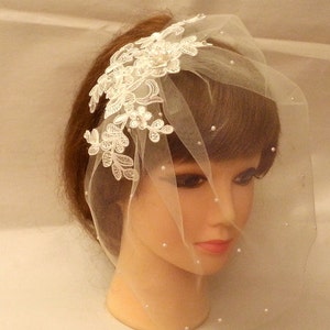 May include: A white bridal veil with a delicate lace design and pearl embellishments. The veil is made of soft tulle and is perfect for a wedding or special occasion.