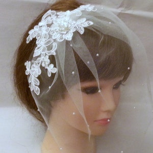 May include: White bridal veil with a delicate lace applique and pearl embellishments. The veil is made of soft tulle and is perfect for a simple and elegant wedding look.