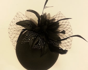 May include: Black and white feather hat with a black net and a black base.