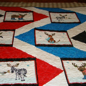 May include: A handmade quilt with a festive winter theme. The quilt features alternating red, white, and blue geometric patterns. Rectangular blocks showcase whimsical animal designs, including reindeer, a penguin, and a zebra, all adorned in winter attire.