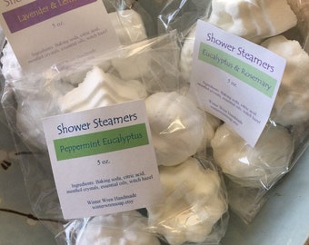 May include: A close-up of three bags of shower steamers. The bags are labeled with the scents: Lavender & Lemon, Peppermint Eucalyptus, and Eucalyptus & Rosemary. Each bag contains several white, round shower steamers.
