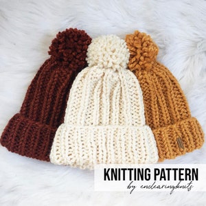 May include: Three knitted hats with pom-poms in brown, white, and yellow. The hats are stacked on top of each other. The text "Knitting Pattern by enclearingknits" is at the bottom of the image.