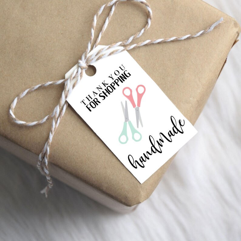 May include: White gift tag with black text that reads "Thank you for shopping handmade". The tag has a pair of pink and green scissors on it.