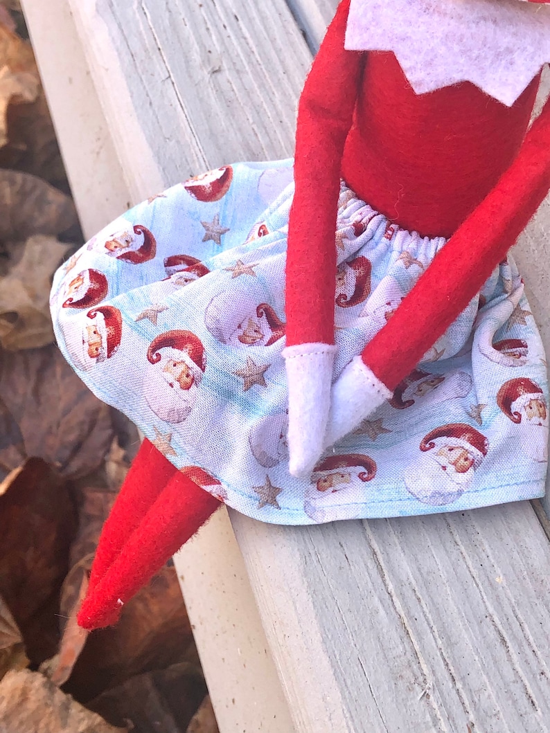 Puede incluir: Una falda de elfo azul y blanca con estampado de Pap&aacute; Noel. La falda tiene una cintura el&aacute;stica blanca y est&aacute; hecha de una tela suave de algod&oacute;n.