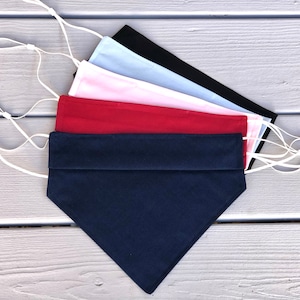May include: Five fabric face masks in different colors, including navy blue, red, pink, white, and black. The masks are folded and have white elastic straps.