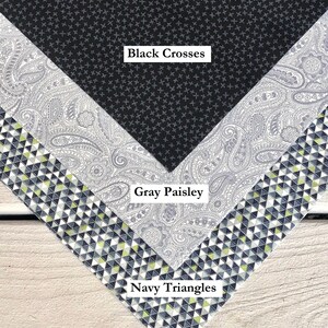 Pu&ograve; includere: Tre campioni di tessuto con diversi motivi. Il campione superiore &egrave; nero con piccole croci bianche. Il campione intermedio &egrave; grigio con un motivo paisley. Il campione inferiore &egrave; blu navy con piccoli triangoli bianchi e gialli.
