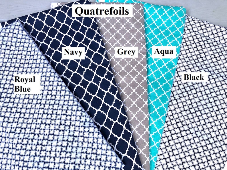 Pu&ograve; includere: Cinque campioni di tessuto con un motivo a quadrifoglio in diversi colori: blu reale, blu navy, grigio, acquamarina e nero. I campioni sono disposti a ventaglio con il testo "Quatrefoils" in alto.