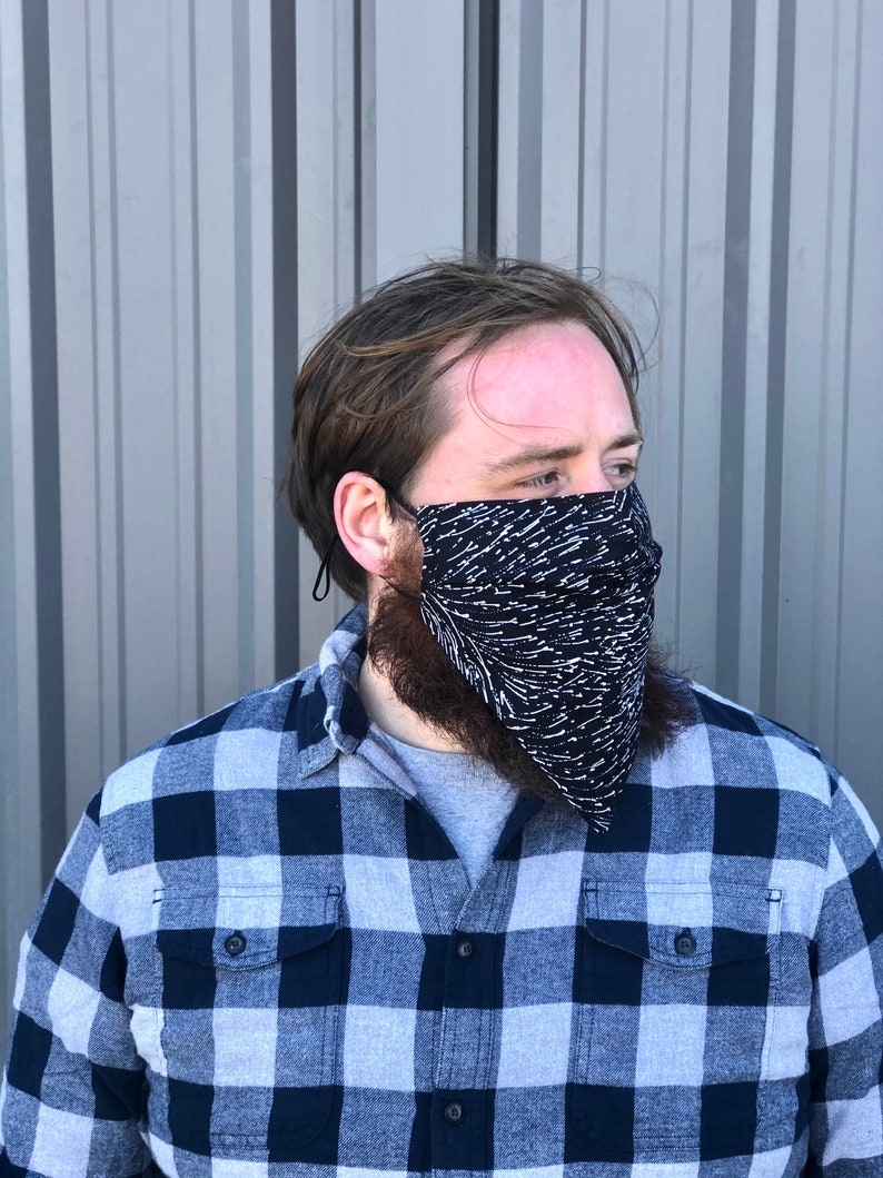 Pu&ograve; includere: Una persona che indossa una camicia a quadri blu e bianca con una maschera facciale a motivi bianchi e neri.