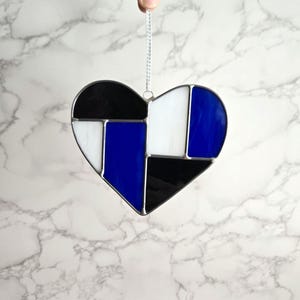 May include: A stained glass heart ornament with a geometric design in black, white, and blue.