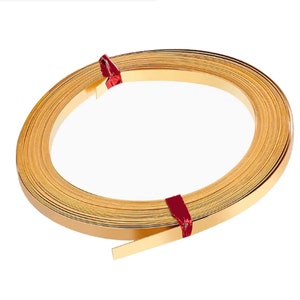 May include: A roll of gold-colored metal trim, tied with red string. The trim is flat and has a shiny finish.
