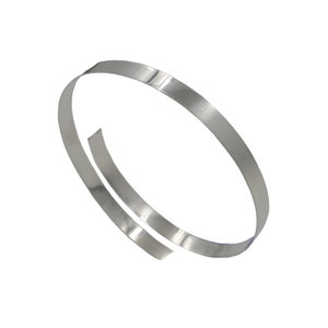 May include: A silver metal band, bent into a circle, is shown in a close-up view. The band is thin and flat, with a smooth surface.