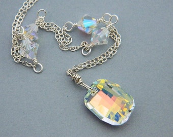 May include: A silver chain necklace with a large iridescent crystal pendant and smaller iridescent crystal accents.