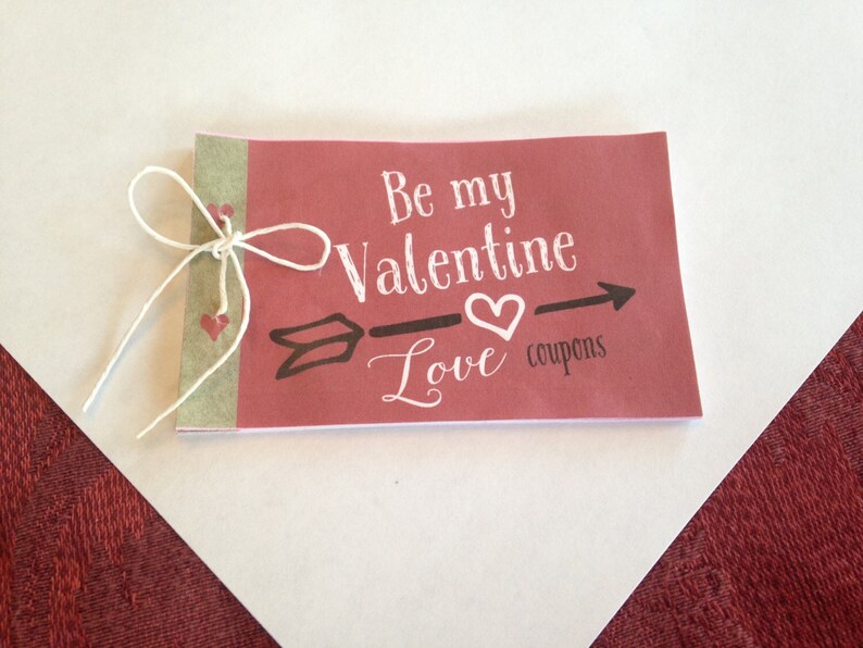 May include: A red booklet with a white string tied around it. The cover says "Be my Valentine - Love coupons".