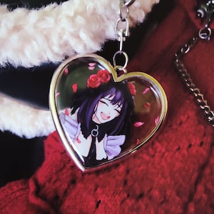 May include: Heart-shaped keychain with a silver border. The image inside features an anime-style character with black hair, a flower crown, and a smiling expression. Pink flower petals are scattered around the character. A silver chain is attached.