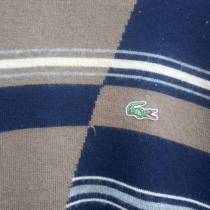 May include: A blue and brown striped sweater with a green crocodile logo.
