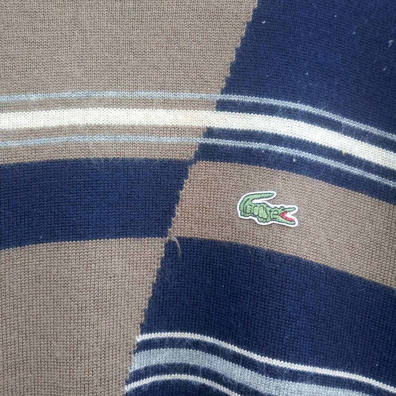 May include: A blue and brown striped sweater with a green crocodile logo.