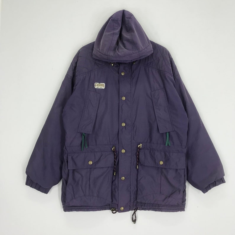May include: A purple hooded jacket with a button-up front, two front pockets, and a drawstring waist. The jacket has a small logo patch on the chest and green accents. The jacket is a vintage style.