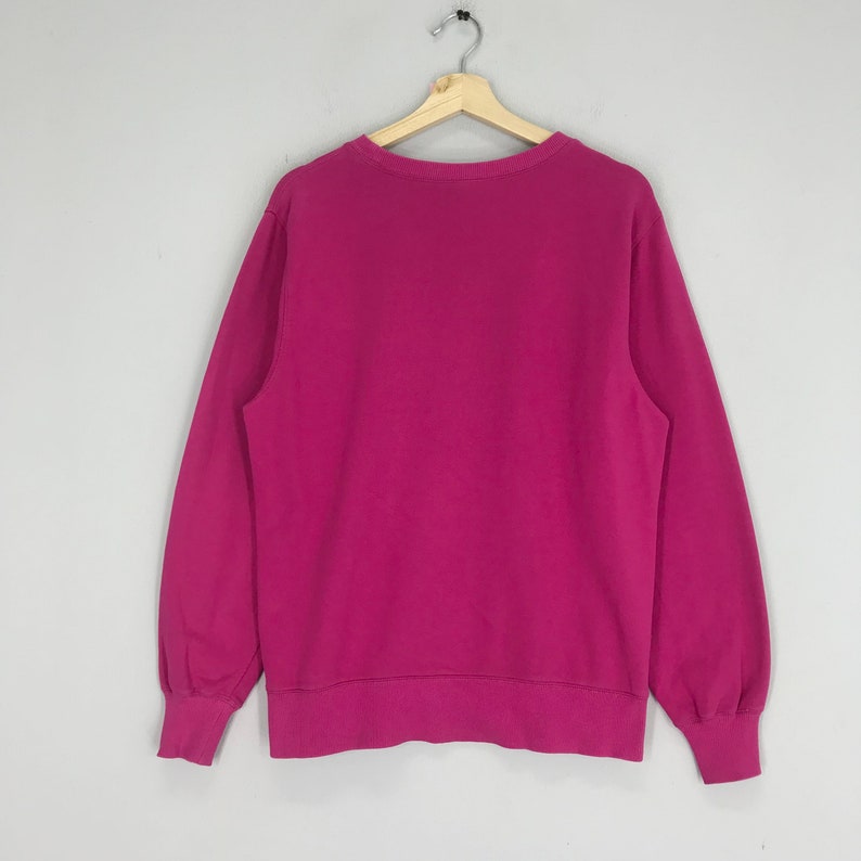 Puede incluir: Una sudadera rosa de cuello redondo y mangas largas.