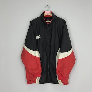 May include: Black, red, and white windbreaker jacket with a zipper closure and a logo on the left chest. The logo is a white stylized letter C with a white rugby ball inside the C.
