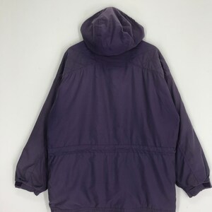 May include: A dark purple hooded jacket with a drawstring waist and long sleeves. The jacket has a quilted design on the shoulders and a velcro closure on the sleeves. The jacket is made of a smooth, durable material.