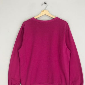 Puede incluir: Una sudadera rosa de manga larga con cuello redondo.