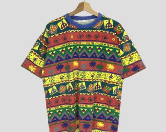 Può includere: Una t-shirt a maniche corte con un motivo geometrico colorato. Il motivo presenta una varietà di forme, tra cui triangoli, cerchi e stelle. La t-shirt è realizzata in un tessuto morbido e confortevole.
