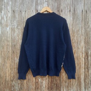 May include: A navy blue long-sleeved sweater with a subtle pattern on the right sleeve.