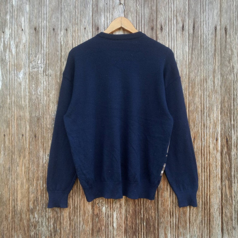 May include: A navy blue long-sleeved sweater with a subtle pattern on the right sleeve.