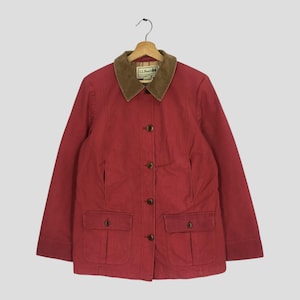 May include: A red jacket with a brown corduroy collar and four brown buttons. The jacket has two front pockets and the brand "L.L.Bean" is visible on the collar. The jacket is hanging on a wooden hanger.
