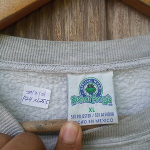 May include: Grey sweatshirt with a white tag that says "Official Wear Senor Frog's MR XL 50% Polyester/50% Algodon Echo en Mexico".
