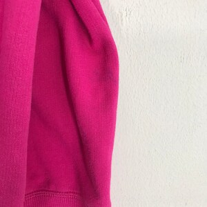 Puede incluir: Primer plano de una tela de sudadera rosa. La tela es suave y texturizada.