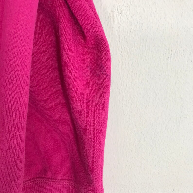 Puede incluir: Primer plano de una tela de sudadera rosa. La tela es suave y texturizada.