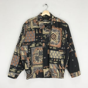 May include: A black button-up jacket with a geometric pattern in shades of brown, beige, and gray. The jacket has a collar and long sleeves.