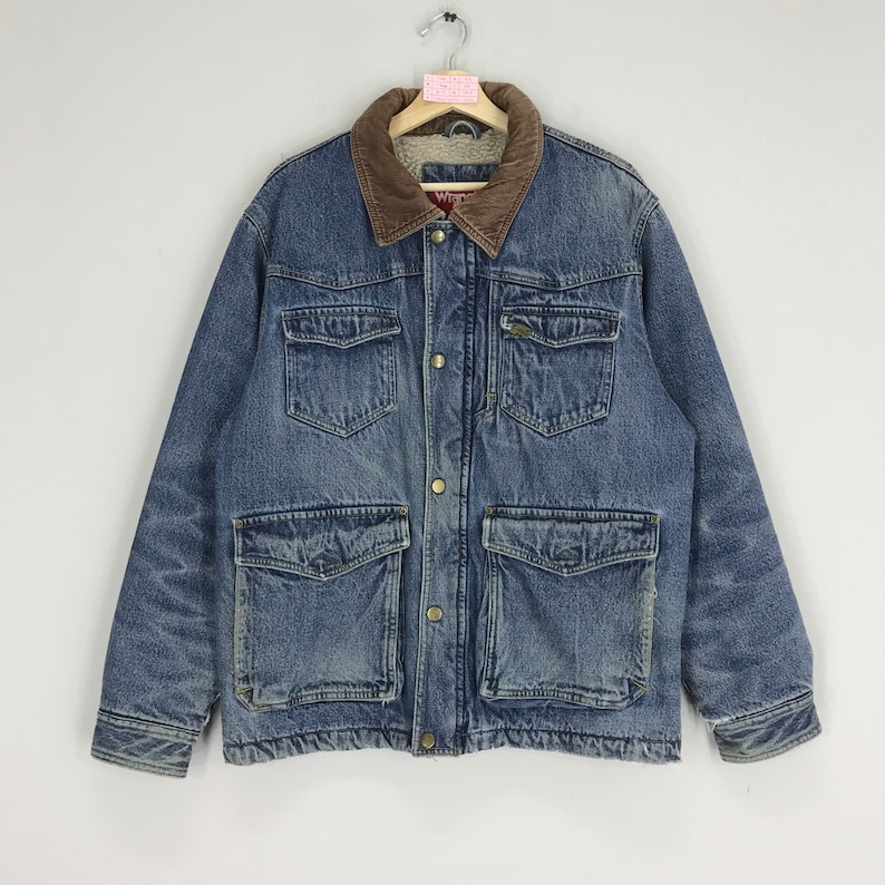 Puede incluir: Una chaqueta vaquera azul con cuello de pana marr&oacute;n y forro de sherpa. La chaqueta tiene dos bolsillos grandes con solapa en la parte delantera y dos bolsillos m&aacute;s peque&ntilde;os en el pecho. La chaqueta tiene cierre de botones y cierre de cremallera.