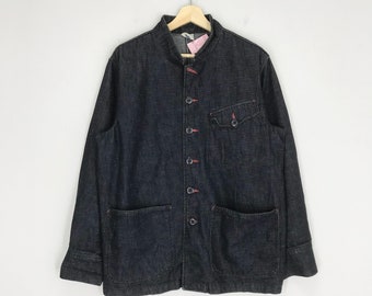 May include: A dark blue denim jacket with a mandarin collar, button closure, and two large pockets. The jacket has red stitching details.