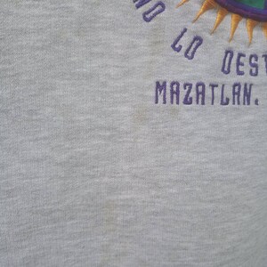 May include: Grey sweatshirt with purple embroidered text that reads "Lo Dest Mazatlan."