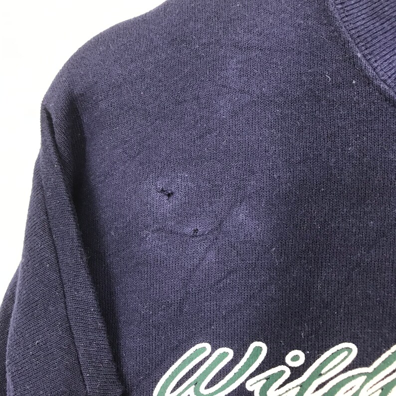 Może przedstawiać: Bordowy sweter z zielono-białym logo "Wildcats" z przodu. Sweter ma małą dziurkę w pobliżu ramienia.