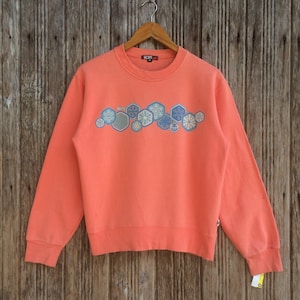 May include: A coral orange sweatshirt with a snowflake design and the word "ROXY" in red on the tag.