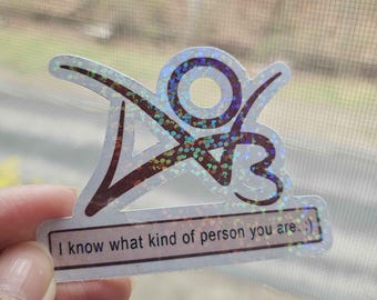 May include: Holographic sticker with a unique design and the text "I know what kind of person you are. :) ". The sticker has a glittery, iridescent finish, with a combination of purple, blue, and silver colors. The design includes abstract shapes and numbers.